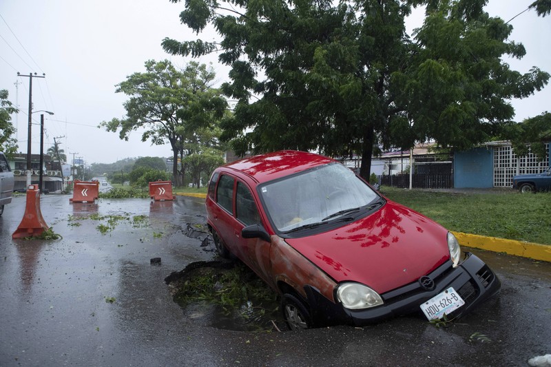 A car is stuck in a flooded street due to Hurricane Rick in Lazaro Cardenas, Mexico, Monday, Oct. 25, 2021. Hurricane Rick roared ashore along Mexico's southern Pacific coast early Monday with winds and heavy rain amid warnings of potential flash floods in the coastal mountains. (AP Photo/Armando Solis)