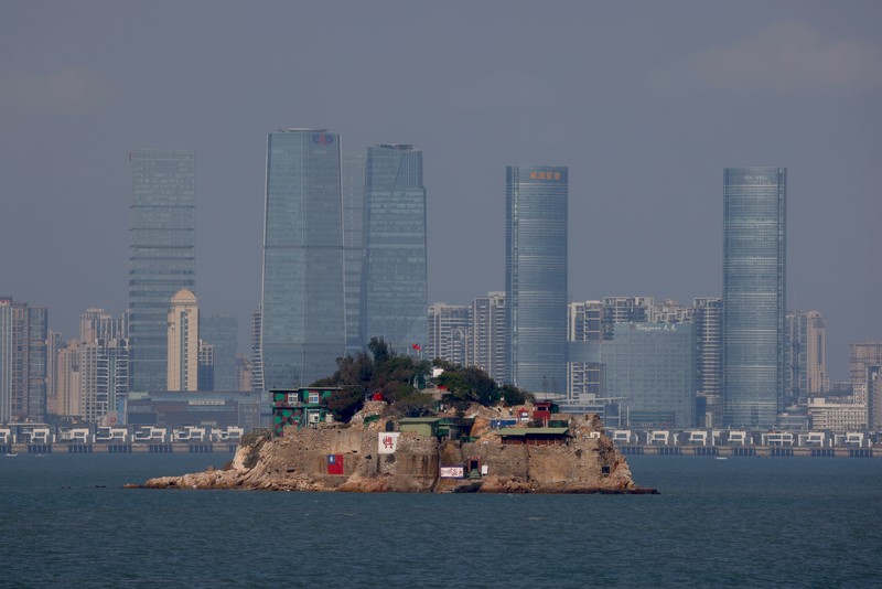 A mannequin of a soldier points a model gun from inside a bunker past Shihyu Islet, towards Xiamen, a coastal city in China, in Lieyu Township, Kinmen, Taiwan, October 19, 2021. Sitting on the front line between Taiwan and China, Kinmen is the last place where the two engaged in major fighting, in 1958 at the height of the Cold War, and where memories of war are burned into minds decades later.  REUTERS/Ann Wang    SEARCH 