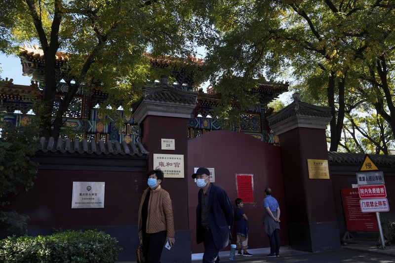 Virus Outbreak China Residents wearing face masks to help curb the spread of the coronavirus walk by a foreigner look at a red notice that reads:
