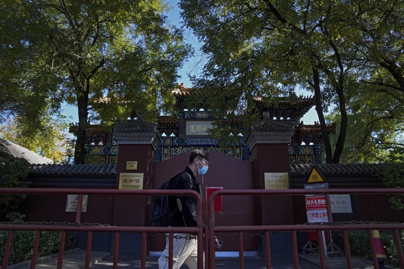 Virus Outbreak China Residents wearing face masks to help curb the spread of the coronavirus walk by a foreigner look at a red notice that reads: