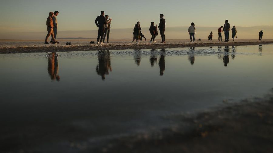 People take photograph and stroll at Tuz lake in Ankara province of Turkey, Tuesday, Oct. 26, 2021. Turkey’s second largest lake and home to several bird species has seen its waters entirely recede this year, a victim of climate change-induced drought that has hit the region as well as decades-long wrongful agricultural policies that have exhausted the lake’s underground waters. (AP Photo/Emrah Gurel)