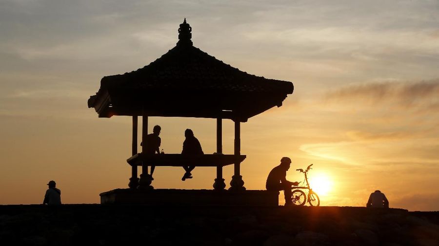 People walk along the beach in Kuta, Bali, Indonesia on Thursday, Oct. 28, 2021. After a summer where COVID-19 infection and death rates soared, officials said this week that they are sticking to plans to allow travel with some limitations, and expects nearly 20 million people to vacation in the popular islands of Java and Bali. (AP Photo/Firdia Lisnawati)