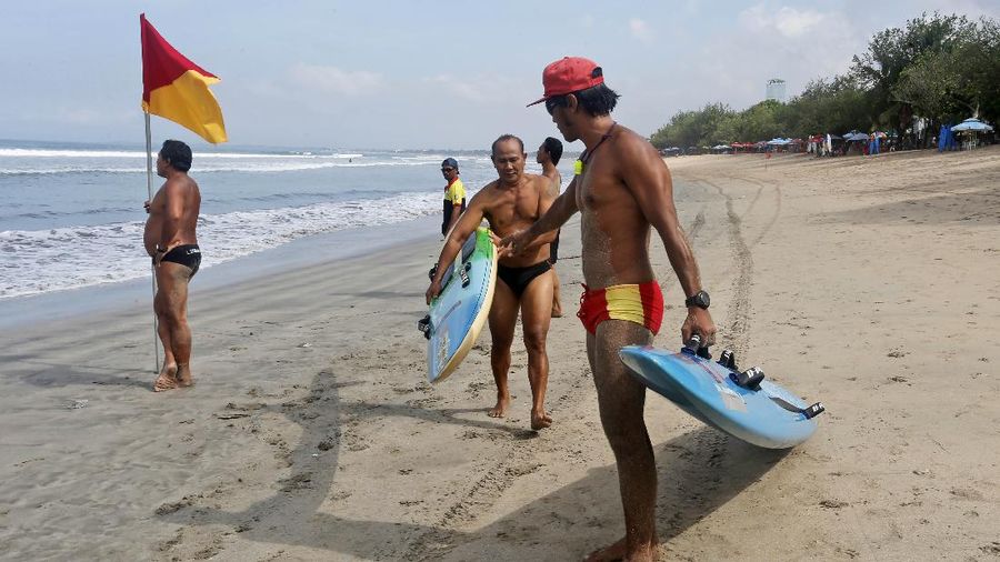 People walk along the beach in Kuta, Bali, Indonesia on Thursday, Oct. 28, 2021. After a summer where COVID-19 infection and death rates soared, officials said this week that they are sticking to plans to allow travel with some limitations, and expects nearly 20 million people to vacation in the popular islands of Java and Bali. (AP Photo/Firdia Lisnawati)