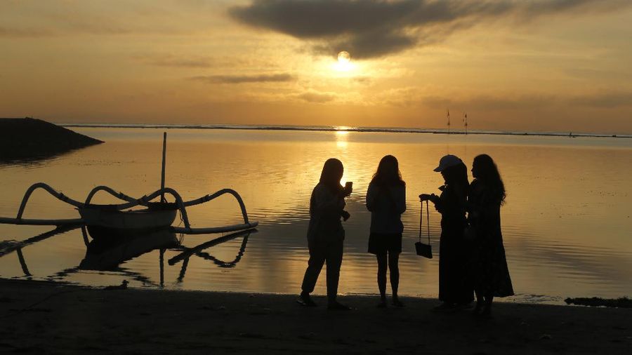 People walk along the beach in Kuta, Bali, Indonesia on Thursday, Oct. 28, 2021. After a summer where COVID-19 infection and death rates soared, officials said this week that they are sticking to plans to allow travel with some limitations, and expects nearly 20 million people to vacation in the popular islands of Java and Bali. (AP Photo/Firdia Lisnawati)