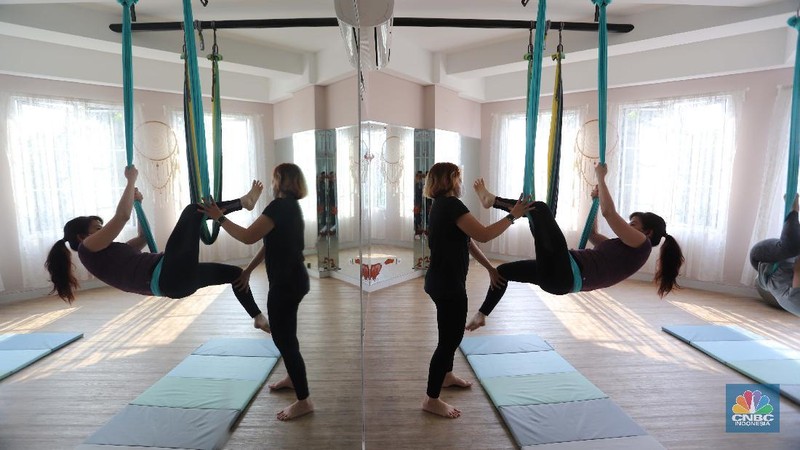 Peserta melakukan gerakan Aerial Yoga (Yoga Udara) di Aerial Jooga Studio di kawasan Kelapa Dua, Banten, Jumat (29/10/2021). Yoga ini menggunakan hammock atau kain yang mengapung untuk menopang berat tubuh seseorang. Kegiatan ini meningkatkan sistem peredaran darah, pernapasan, dan pencernaan Anda, serta memperkuat otot dan persendian. Ambil napas dalam-dalam dan lepaskan pikiran dan tubuh Anda dari tekanan hidup dan gravitasi. Olahraga yang identik dengan penggunaan kain serupa hammock ini terbukti sukses mempertahankan stamina dan badannya yang ramping. Flying yoga atau disebut aerial yoga bisa jadi alternatif bagi yang ingin mempertahankan kesehatan. Studi American Council on Exercise (ACE) menyatakan, wanita yang melakukan flying yoga tiga kali seminggu dalam 50 menit selama 6 minggu bisa kehilangan berat badan 1 kilogram. (CNBC Indonesia/ Muhammad Sabki)