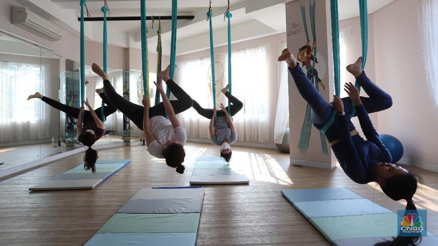 Peserta melakukan gerakan Aerial Yoga (Yoga Udara) di Aerial Jooga Studio di kawasan Kelapa Dua, Banten, Jumat (29/10/2021). Yoga ini menggunakan hammock atau kain yang mengapung untuk menopang berat tubuh seseorang. Kegiatan ini meningkatkan sistem peredaran darah, pernapasan, dan pencernaan Anda, serta memperkuat otot dan persendian. Ambil napas dalam-dalam dan lepaskan pikiran dan tubuh Anda dari tekanan hidup dan gravitasi. Olahraga yang identik dengan penggunaan kain serupa hammock ini terbukti sukses mempertahankan stamina dan badannya yang ramping. Flying yoga atau disebut aerial yoga bisa jadi alternatif bagi yang ingin mempertahankan kesehatan. Studi American Council on Exercise (ACE) menyatakan, wanita yang melakukan flying yoga tiga kali seminggu dalam 50 menit selama 6 minggu bisa kehilangan berat badan 1 kilogram. (CNBC Indonesia/ Muhammad Sabki)