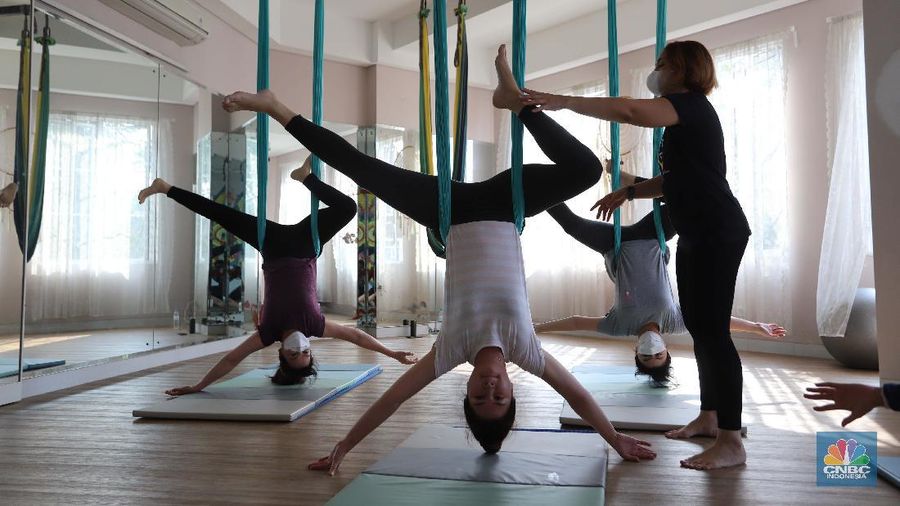 Peserta melakukan gerakan Aerial Yoga (Yoga Udara) di Aerial Jooga Studio di kawasan Kelapa Dua, Banten, Jumat (29/10/2021). Yoga ini menggunakan hammock atau kain yang mengapung untuk menopang berat tubuh seseorang. Kegiatan ini meningkatkan sistem peredaran darah, pernapasan, dan pencernaan Anda, serta memperkuat otot dan persendian. Ambil napas dalam-dalam dan lepaskan pikiran dan tubuh Anda dari tekanan hidup dan gravitasi. Olahraga yang identik dengan penggunaan kain serupa hammock ini terbukti sukses mempertahankan stamina dan badannya yang ramping. Flying yoga atau disebut aerial yoga bisa jadi alternatif bagi yang ingin mempertahankan kesehatan. Studi American Council on Exercise (ACE) menyatakan, wanita yang melakukan flying yoga tiga kali seminggu dalam 50 menit selama 6 minggu bisa kehilangan berat badan 1 kilogram. (CNBC Indonesia/ Muhammad Sabki)