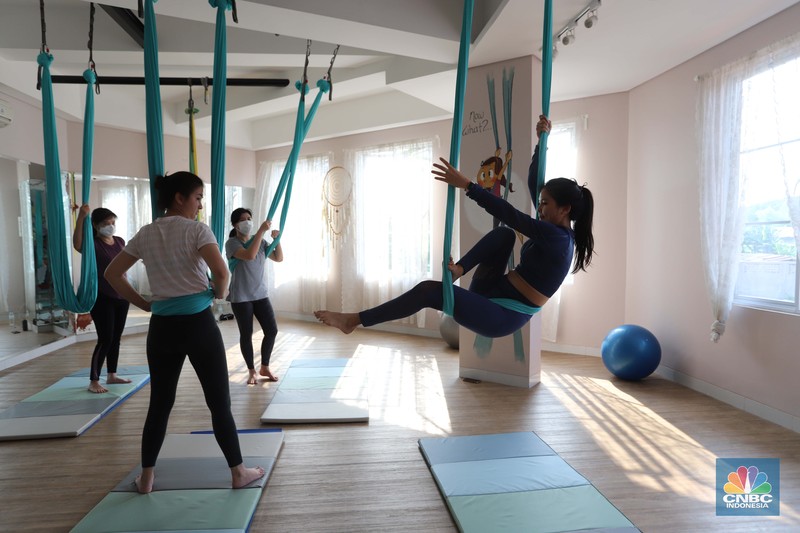 Peserta melakukan gerakan Aerial Yoga (Yoga Udara) di Aerial Jooga Studio di kawasan Kelapa Dua, Banten, Jumat (29/10/2021). Yoga ini menggunakan hammock atau kain yang mengapung untuk menopang berat tubuh seseorang. Kegiatan ini meningkatkan sistem peredaran darah, pernapasan, dan pencernaan Anda, serta memperkuat otot dan persendian. Ambil napas dalam-dalam dan lepaskan pikiran dan tubuh Anda dari tekanan hidup dan gravitasi. Olahraga yang identik dengan penggunaan kain serupa hammock ini terbukti sukses mempertahankan stamina dan badannya yang ramping. Flying yoga atau disebut aerial yoga bisa jadi alternatif bagi yang ingin mempertahankan kesehatan. Studi American Council on Exercise (ACE) menyatakan, wanita yang melakukan flying yoga tiga kali seminggu dalam 50 menit selama 6 minggu bisa kehilangan berat badan 1 kilogram. (CNBC Indonesia/ Muhammad Sabki)