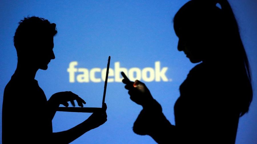 FILE PHOTO: People are silhouetted as they pose with laptops in front of a screen projected with a Facebook logo, in this picture illustration taken in Zenica October 29, 2014. REUTERS/Dado Ruvic/File Photo