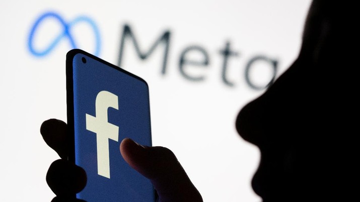 Meta dan facebook Woman holds smartphone with Facebook logo in front of a displayed Facebook's new rebrand logo Meta in this illustration picture taken October 28, 2021. REUTERS/Dado Ruvic/Illustration