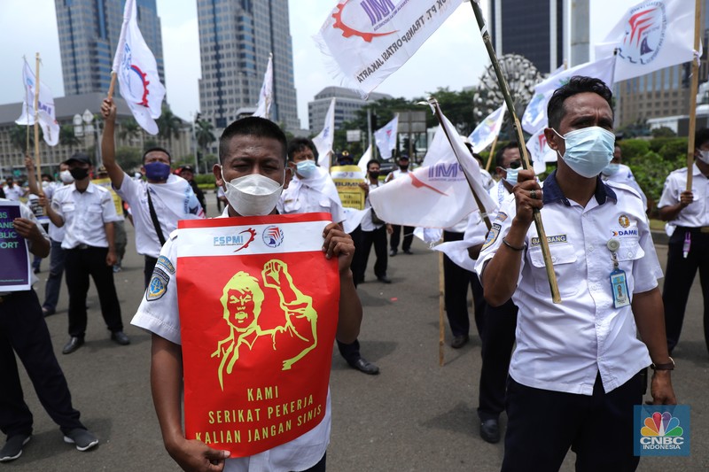 Puluhan massa pekerja dari Serikat Pekerja Dirgantara dan Transportasi (SPDT) Federasi Serikat Pekerja Metal Indonesia (FSPMI) menggelar aksi di Patung Kuda, Jakarta, Senin (1/11/2021). Aksi unjuk rasa digelar hari ini bertujuan sebagai upaya mereka mendesak kepada perum DAMRI agar membayar upah para karyawan yang sudah menunggak. Termasuk hal-hal lain yang belum dipenuhi oleh jasa transportasi. Pantauan dilokasi petugas kepolisian berjaga menggunakan pakaian Hazmat.  (CNBC Indonesia/ Tri Susilo)