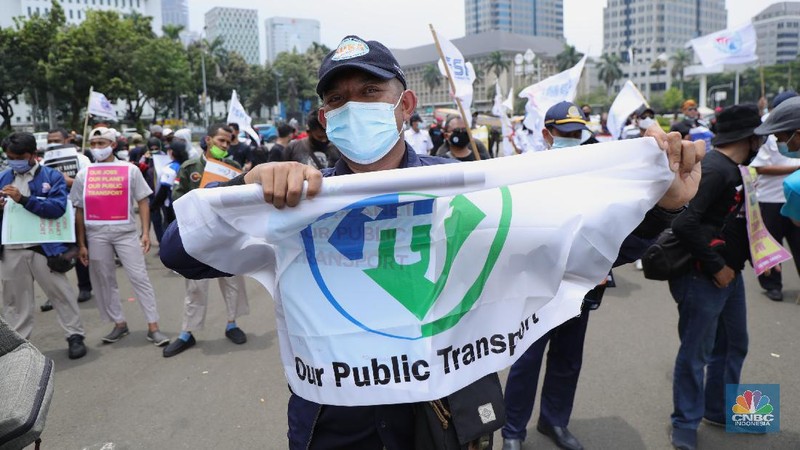 Puluhan massa pekerja dari Serikat Pekerja Dirgantara dan Transportasi (SPDT) Federasi Serikat Pekerja Metal Indonesia (FSPMI) menggelar aksi di Patung Kuda, Jakarta, Senin (1/11/2021). Aksi unjuk rasa digelar hari ini bertujuan sebagai upaya mereka mendesak kepada perum DAMRI agar membayar upah para karyawan yang sudah menunggak. Termasuk hal-hal lain yang belum dipenuhi oleh jasa transportasi. Pantauan dilokasi petugas kepolisian berjaga menggunakan pakaian Hazmat.  (CNBC Indonesia/ Tri Susilo)