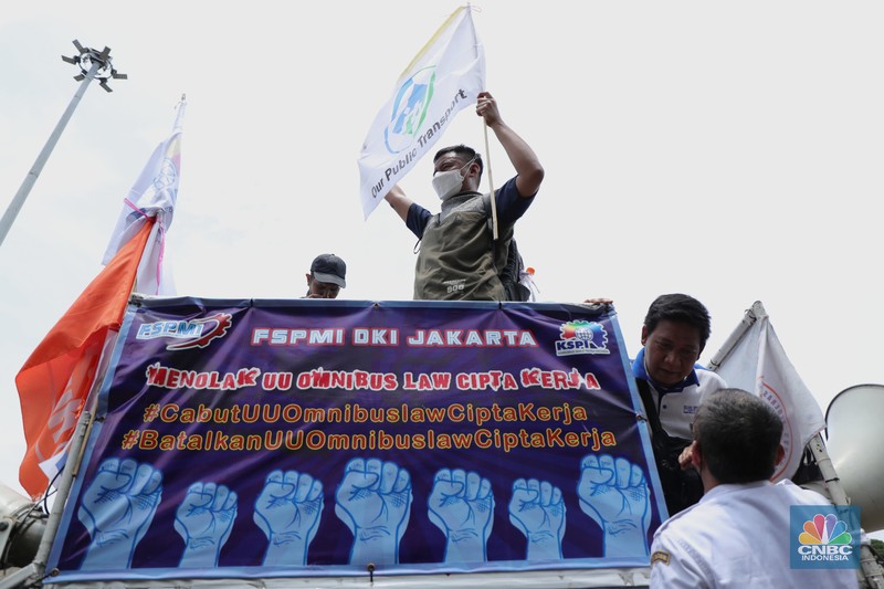 Puluhan massa pekerja dari Serikat Pekerja Dirgantara dan Transportasi (SPDT) Federasi Serikat Pekerja Metal Indonesia (FSPMI) menggelar aksi di Patung Kuda, Jakarta, Senin (1/11/2021). Aksi unjuk rasa digelar hari ini bertujuan sebagai upaya mereka mendesak kepada perum DAMRI agar membayar upah para karyawan yang sudah menunggak. Termasuk hal-hal lain yang belum dipenuhi oleh jasa transportasi. Pantauan dilokasi petugas kepolisian berjaga menggunakan pakaian Hazmat.  (CNBC Indonesia/ Tri Susilo)
