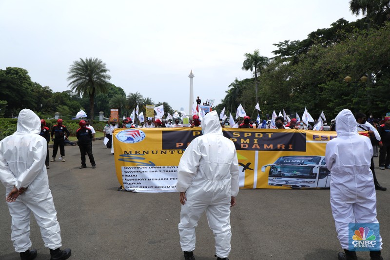 Demo Pegawai DAMRI Desak Gaji Pegawai Segera Dibayarkan Puluhan massa pekerja dari Serikat Pekerja Dirgantara dan Transportasi (SPDT) Federasi Serikat Pekerja Metal Indonesia (FSPMI) menggelar aksi di Patung Kuda, Jakarta, Senin (1/11/2021). Aksi unjuk rasa digelar hari ini bertujuan sebagai upaya mereka mendesak kepada perum DAMRI agar membayar upah para karyawan yang sudah menunggak. Termasuk hal-hal lain yang belum dipenuhi oleh jasa transportasi. Pantauan dilokasi petugas kepolisian berjaga menggunakan pakaian Hazmat. (CNBC Indonesia/ Tri Susilo)