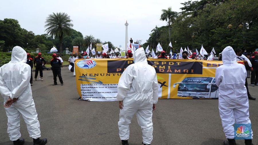 Puluhan massa pekerja dari Serikat Pekerja Dirgantara dan Transportasi (SPDT) Federasi Serikat Pekerja Metal Indonesia (FSPMI) menggelar aksi di Patung Kuda, Jakarta, Senin (1/11/2021). Aksi unjuk rasa digelar hari ini bertujuan sebagai upaya mereka mendesak kepada perum DAMRI agar membayar upah para karyawan yang sudah menunggak. Termasuk hal-hal lain yang belum dipenuhi oleh jasa transportasi. Pantauan dilokasi petugas kepolisian berjaga menggunakan pakaian Hazmat.  (CNBC Indonesia/ Tri Susilo)