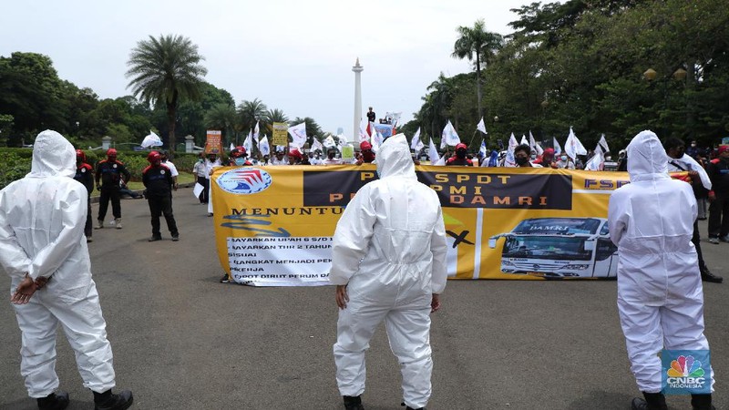 Puluhan massa pekerja dari Serikat Pekerja Dirgantara dan Transportasi (SPDT) Federasi Serikat Pekerja Metal Indonesia (FSPMI) menggelar aksi di Patung Kuda, Jakarta, Senin (1/11/2021). Aksi unjuk rasa digelar hari ini bertujuan sebagai upaya mereka mendesak kepada perum DAMRI agar membayar upah para karyawan yang sudah menunggak. Termasuk hal-hal lain yang belum dipenuhi oleh jasa transportasi. Pantauan dilokasi petugas kepolisian berjaga menggunakan pakaian Hazmat.  (CNBC Indonesia/ Tri Susilo)