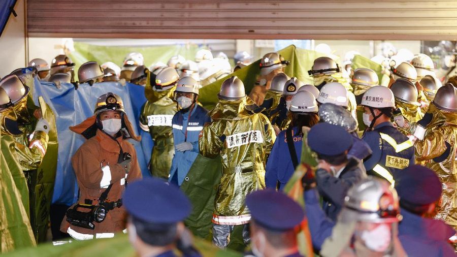 Emergency workers and police officers at a train station in Tokyo, Sunday Oct. 31, 2021 after a man brandishing a knife on a commuter train stabbed several passengers before starting a fire, which sent people scrambling to escape and jumping from windows, police and witness said. (Kyodo News via AP)