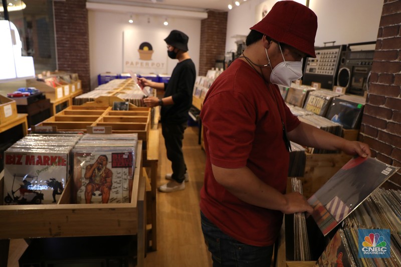 Pengunjung memilih piringan hitam di sebuah toko musik Paper Pot Record di kawasan Blok M, Jakarta, Senin (1/11/2021). Toko tersebut menjual koleksi piringan hitam yang diproduksi pada tahun 1950-an dengan harga Rp75 ribu hingga Rp200 ribu per keping, totalnya dengan koleksi sekitar 10.000 pirangan hitam. Toko piringan hitam di Jakarta yang masih tergolong baru ini terletak di dalam Blok M Plaza lantai 4, Bulungan, Jakarta Selatan. Menggunakan strategi cheapo box dimana puluhan rak berisi piringan hitam bekas dijual satuan hanya seharga 75rb, Paper Pot Records bisa menjadi pilihan kamu yang penasaran sama piringan hitam dan ingin membeli piringan hitam pertama untuk dikoleksi. Menurut pemilik, Ardi (31) selain ratusan piringan hitam murah, Paper Pot juga menjual beberapa piringan hitam yang tergolong langka dengan harga yang cukup miring untuk genre hip hop, rock, dan jazz