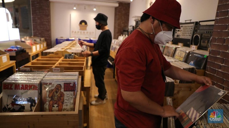 Pengunjung memilih piringan hitam di sebuah toko musik Paper Pot Record di kawasan Blok M, Jakarta, Senin (1/11/2021). Toko tersebut menjual koleksi piringan hitam yang diproduksi pada tahun 1950-an dengan harga Rp75 ribu hingga Rp200 ribu per keping, totalnya dengan koleksi sekitar 10.000 pirangan hitam. Toko piringan hitam di Jakarta yang masih tergolong baru ini terletak di dalam Blok M Plaza lantai 4, Bulungan, Jakarta Selatan. Menggunakan strategi cheapo box dimana puluhan rak berisi piringan hitam bekas dijual satuan hanya seharga 75rb, Paper Pot Records bisa menjadi pilihan kamu yang penasaran sama piringan hitam dan ingin membeli piringan hitam pertama untuk dikoleksi. Menurut pemilik, Ardi (31) selain ratusan piringan hitam murah, Paper Pot juga menjual beberapa piringan hitam yang tergolong langka dengan harga yang cukup miring untuk genre hip hop, rock, dan jazz