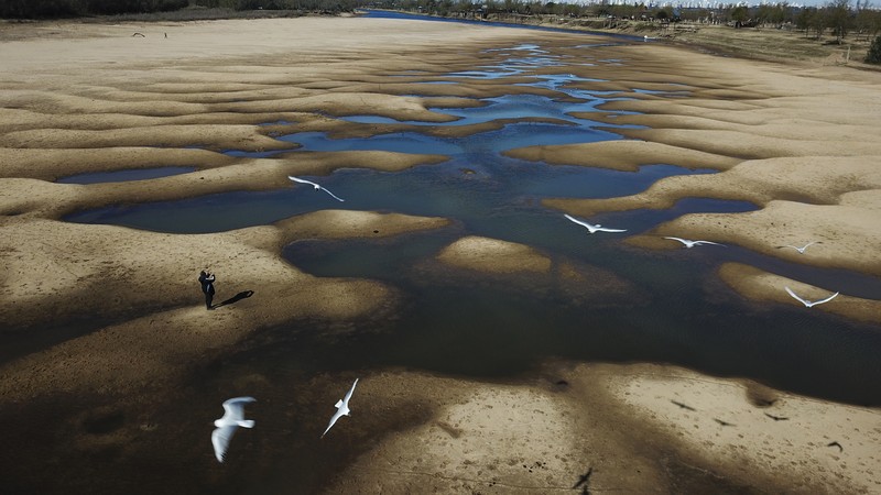 A kayaker fishes in Lake Oroville as water levels remain low due to continuing drought conditions in Oroville, Calif., Aug. 22, 2021. (AP Photo/Ethan Swope)