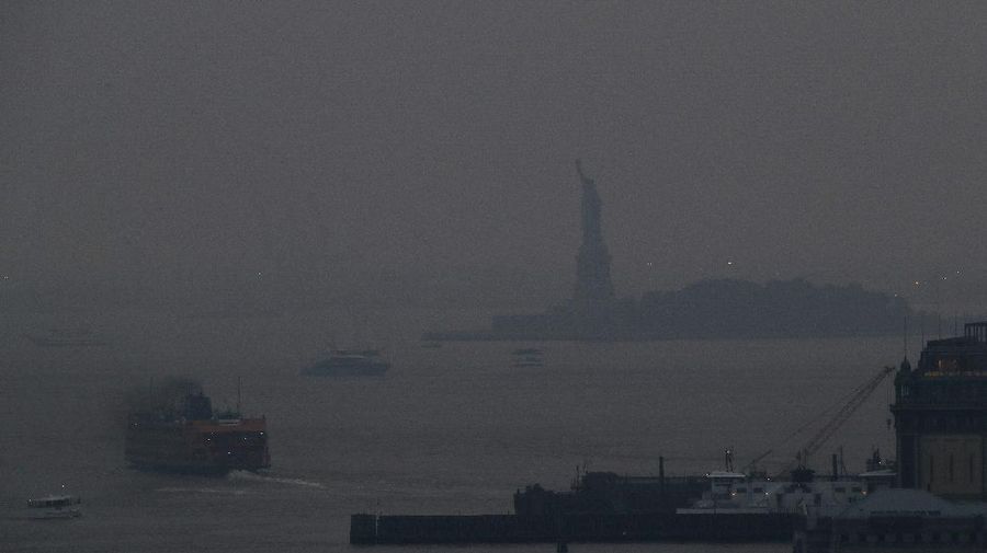 The Staten Island Ferry departs from the Manhattan terminal through a haze of smoke with the Statue of Liberty barely visible, Tuesday, July 20, 2021, in New York. Wildfires in the American West, including one in Oregon created hazy skies as far away as New York. (AP Photo/Julie Jacobson)