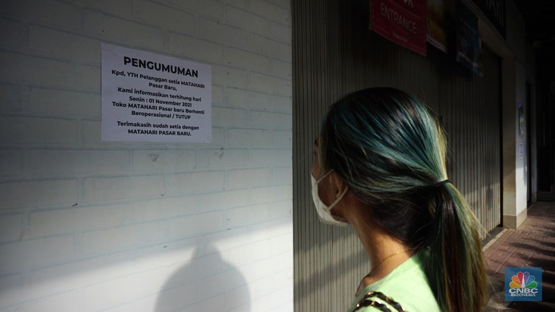 Suasana Matahari Pasar Baru yang Tutup Warga melihat selembaran kertas yang tertempel digerai Matahari Store, Pasar Baru, Jakarta, Selasa (2/11/2021). Matahari Departemen Store menutup gerainya yang ada di Pasar Baru, didrpan lokasi hanya terpakir kendaraan pengunjung gerai lain. Menurut petugas parkir