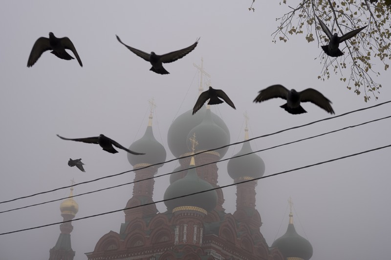 A pedestrian walk through morning fog along a pond in Ostankino in Moscow, Russia, Tuesday, Nov. 2, 2021. More than 30 flights were delayed or canceled at three airports in the capital due to fog. (AP Photo/Alexander Zemlianichenko)