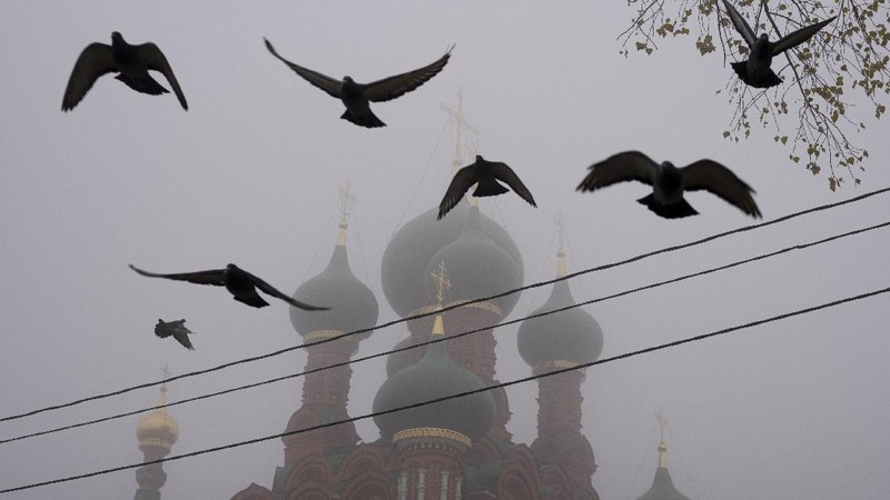 A pedestrian walk through morning fog along a pond in Ostankino in Moscow, Russia, Tuesday, Nov. 2, 2021. More than 30 flights were delayed or canceled at three airports in the capital due to fog. (AP Photo/Alexander Zemlianichenko)
