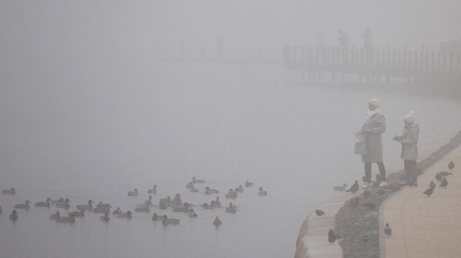 A pedestrian walk through morning fog along a pond in Ostankino in Moscow, Russia, Tuesday, Nov. 2, 2021. More than 30 flights were delayed or canceled at three airports in the capital due to fog. (AP Photo/Alexander Zemlianichenko)