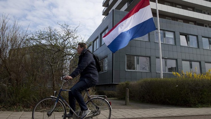 A bicyclist passes a Dutch flag flying half-staff at the site of a shooting incident in a tram in Utrecht, Netherlands, Tuesday, March 19, 2019. A gunman killed three people and wounded others on a tram in the central Dutch city of Utrecht Monday March 18, 2019. (AP Photo/Peter Dejong)