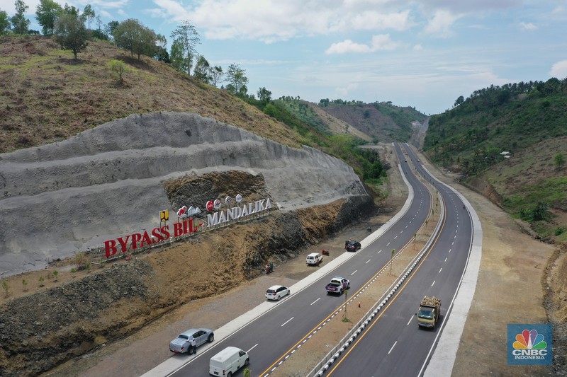 Bypass Bil Mandalika, Lombok Foto udara menunjukkan pendendara melewati jalan Bypass Bil Mandalika, Lombok, Nusa Tenggara Barat, Kamis (4/1/2021). Kementerian Pekerjaan Umum & Perumahan Rakyat (PUPR) melalui Badan Pengembangan Infrastruktur Wilayah (BPIW) membangun jalan elak atau bypass yang menghubungkan Bandara Internasional Lombok dengan Kawasan Pariwisata Mandalika sejauh 17 kilometer. Keberadaan jalan ini bakal mendukung aktivitas pariwisata di Mandalika seiring rencana penyelenggaraan balap motor MotoGP pada 2021 mendatang. Pembangunan jalan ini akan meningkatkan konektivitas dari Bandara BIL ke Kawasan Wisata Mandalika dan mendukung akses menuju sirkuit MotoGP yang dibangun di Kawasan Mandalika. Jalan ini juga akan mengurangi waktu tempuh dari BIL ke Mandalika menjadi 15 menit. Sebab, jika semula melewati jalan lama bisa lebih dari 45 menit. Jalan Bypass BIL-Mandalika memiliki panjang 17,363 kilometer dengan lebar right of way (ROW) 50 meter serta 4 lajur yang dilengkapi median jalan. Menelan anggaran sekitar Rp 706 miliar pada 2020–2021. Pembangunannya terdiri dari tiga paket pekerjaan. Yakni Paket I sepanjang 4,30 km (STA 0+000-STA 4+300) dengan kontraktor PT Nindya Karya-Bumi Agung (KSO) dengan anggaran sebesar Rp199 miliar. Kemudian Paket 2 sepanjang 9,70 km (STA 4+300-STA 14+000) kontraktornya PT Adhi Karya (Persero) Tbk-PT Metro Lestari Utama (KSO) dengan anggaran senilai Rp 353 miliar. Selanjutnya untuk Paket 3 sepanjang 3,363 km (STA 14+00-STA 17+363), kontraktornya PT Yasa Patria Perkasa dengan anggaran senilai Rp 152 miliar. (CNBC Indonesia/ Tri Susilo)