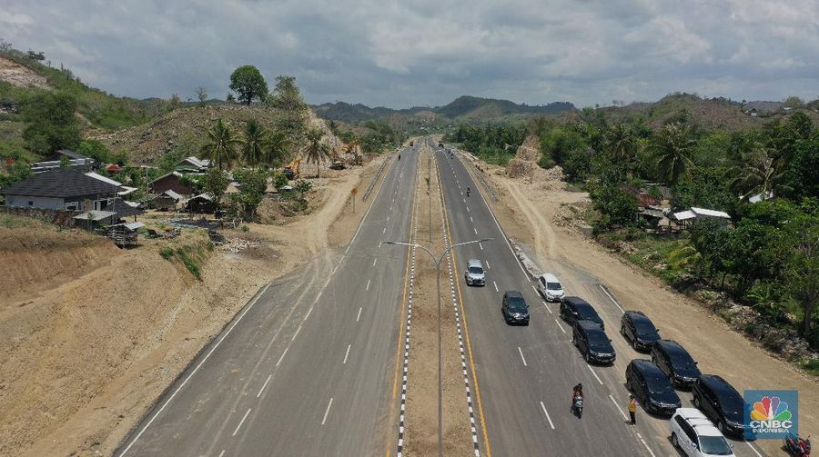 Foto udara menunjukkan pendendara melewati jalan Bypass Bil Mandalika, Lombok, Nusa Tenggara Barat, Kamis (4/1/2021).  Kementerian Pekerjaan Umum & Perumahan Rakyat (PUPR) melalui Badan Pengembangan Infrastruktur Wilayah (BPIW) membangun jalan elak atau bypass yang menghubungkan Bandara Internasional Lombok dengan Kawasan Pariwisata Mandalika sejauh 17 kilometer. Keberadaan jalan ini bakal mendukung aktivitas pariwisata di Mandalika seiring rencana penyelenggaraan balap motor MotoGP pada 2021 mendatang. Pembangunan jalan ini akan meningkatkan konektivitas dari Bandara BIL ke Kawasan Wisata Mandalika dan mendukung akses menuju sirkuit MotoGP yang dibangun di Kawasan Mandalika. Jalan ini juga akan mengurangi waktu tempuh dari BIL ke Mandalika menjadi 15 menit. Sebab, jika semula melewati jalan lama bisa lebih dari 45 menit.  Jalan Bypass BIL-Mandalika memiliki panjang 17,363 kilometer dengan lebar right of way (ROW) 50 meter serta 4 lajur yang dilengkapi median jalan. Menelan anggaran sekitar Rp 706 miliar pada 2020–2021. Pembangunannya terdiri dari tiga paket pekerjaan. Yakni Paket I sepanjang 4,30 km (STA 0+000-STA 4+300) dengan kontraktor PT Nindya Karya-Bumi Agung (KSO) dengan anggaran sebesar Rp199 miliar. Kemudian Paket 2 sepanjang 9,70 km (STA 4+300-STA 14+000) kontraktornya PT Adhi Karya (Persero) Tbk-PT Metro Lestari Utama (KSO) dengan anggaran senilai Rp 353 miliar. Selanjutnya untuk Paket 3 sepanjang 3,363 km (STA 14+00-STA 17+363), kontraktornya PT Yasa Patria Perkasa dengan anggaran senilai Rp 152 miliar.  (CNBC Indonesia/ Tri Susilo)