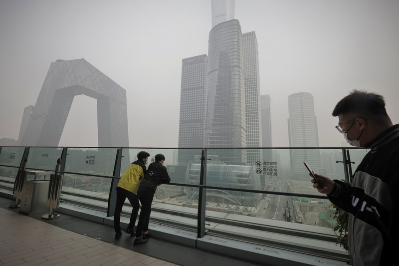 People overlook the skyline of the Central Business District on a polluted day in Beijing, China, November 5, 2021.  REUTERS/Thomas Peter