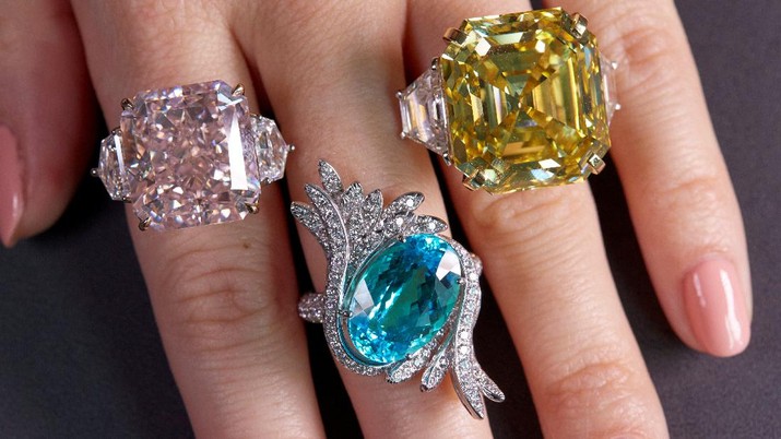 lelang Berlian A staff wears an orange-pink diamond ring weighing 25.62 carats, a tourmaline and diamond ring weighing 9.88 carats and a yellow diamond ring weighing 25.88 carats, during a preview at Sotheby's, before their auction sale in Geneva, Switzerland, November 2, 2021. REUTERS/Denis Balibouse