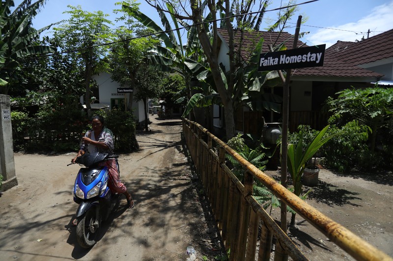 Petugas berbincang dengan warga berlatar belakang Sarana Hunian Pariwisata atau Sarhunta di Kampung Homestay di Dusun Bangan, Desa Sengkol, Kecamatan Pujut, Lombok Tengah, Nusa Tenggara Barat, Jumat (5/11/2021). Kementerian PUPR melalui Balai Pelaksana Penyediaan Perumahan Nusa Tenggara I (BPPNT I) meningkatkan kualitas 300 rumah tak layak huni menjadi Sarana Hunian Pariwisata atau Sarhunta. Balai Perumahan, Kasi Wilayah 2 Nusa Tenggara Barat Dudi Mustofa, mengatakan kegiatan peningkatan kualitas hunian dimulai dari tahun 2020, tepatnya perencanaan di bulan Mei dan pelaksanaan fisik kegiatannya tanggal 17 Agustus 2020 sampai dengan 31 Desember 2020. Berada di Kawasan Mandalika ada 300 rumah dan di kawasan Gili Air ada 98 rumah,