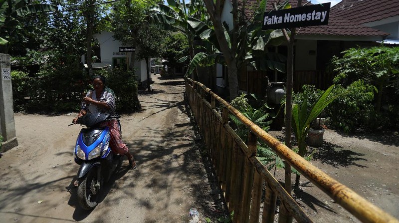 Petugas berbincang dengan warga berlatar belakang Sarana Hunian Pariwisata atau Sarhunta di Kampung Homestay di Dusun Bangan, Desa Sengkol, Kecamatan Pujut, Lombok Tengah, Nusa Tenggara Barat, Jumat (5/11/2021). Kementerian PUPR melalui Balai Pelaksana Penyediaan Perumahan Nusa Tenggara I (BPPNT I) meningkatkan kualitas 300 rumah tak layak huni menjadi Sarana Hunian Pariwisata atau Sarhunta. Balai Perumahan, Kasi Wilayah 2 Nusa Tenggara Barat Dudi Mustofa, mengatakan kegiatan peningkatan kualitas hunian dimulai dari tahun 2020, tepatnya perencanaan di bulan Mei dan pelaksanaan fisik kegiatannya tanggal 17 Agustus 2020 sampai dengan 31 Desember 2020. Berada di Kawasan Mandalika ada 300 rumah dan di kawasan Gili Air ada 98 rumah,