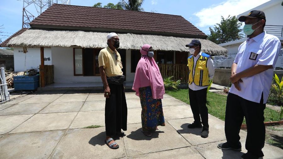 Petugas berbincang dengan warga berlatar belakang Sarana Hunian Pariwisata atau Sarhunta di Kampung Homestay di Dusun Bangan, Desa Sengkol, Kecamatan Pujut, Lombok Tengah, Nusa Tenggara Barat, Jumat (5/11/2021). Kementerian PUPR melalui Balai Pelaksana Penyediaan Perumahan Nusa Tenggara I (BPPNT I) meningkatkan kualitas 300 rumah tak layak huni menjadi Sarana Hunian Pariwisata atau Sarhunta. Balai Perumahan, Kasi Wilayah 2 Nusa Tenggara Barat Dudi Mustofa, mengatakan kegiatan peningkatan kualitas hunian dimulai dari tahun 2020, tepatnya perencanaan di bulan Mei dan pelaksanaan fisik kegiatannya tanggal 17 Agustus 2020 sampai dengan 31 Desember 2020. Berada di Kawasan Mandalika ada 300 rumah dan di kawasan Gili Air ada 98 rumah,