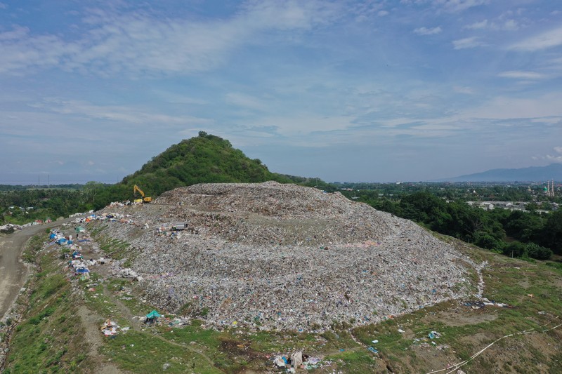 Tempat Pembuangan Akhir (TPA) Regional Kebon Kongok, Kabupaten Lombok Barat, Foto udara gunungan sampah di Tempat Pembuangan Akhir (TPA) Regional Kebon Kongok, Kabupaten Lombok Barat, Jumat (5/11/2021). Lokasi ini merupakan tempat pemilahan sampah organik dan anorganik, di komplek TPA terbesar di Nusa Tenggara Barat NTB. Dari sini, proses pengolahan sampah menjadi pelet RDF (Refuse Derived Fuel) dibuat, yang merupakan pengganti bahan bakar batubara di Pembangkit Listrik Tenaga Uap (PLTU) Jeranjang, Lombok Barat. Sampah diproses di mesin pencacah ukuran 5-8 mm untuk berikutnya dimasukkan ke mesin pengepresan menjadi pelet RDF. Pelet akan dikeringkan di bawah sinar matahari sebelum dikirim ke PLTU Jeranjang. Di pembangkit listrik itu pelet dibakar melalui sistem co-firing.
Setiap hari, sekitar 300 ton sampah dari Kota Mataram dan Lombok Barat diantar ke TPA ini. Namun, menurut jumlah yang diolah menjadi pellet baru 100 hingga 200 kilogram.
Kementerian PUPR memfasilitasi lahan seluas 40 are (4 ribu meter persegi) di sekitar TPA. Di bangunan tersebut, semua fasilitas yang dibutuhkan untuk pengolahan sampah menjadi pellet disediakan.
Penelitian masih dilakukan agar sampah non-organik bisa lebih banyak diolah. Saat ini, komposisi pelet terdiri 95 persen sampah organik dan 5 persen anorganik. (CNBC Indonesia/ Tri Susilo)