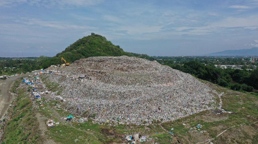Foto udara gunungan sampah di Tempat Pembuangan Akhir (TPA) Regional Kebon Kongok, Kabupaten Lombok Barat, Jumat (5/11/2021).  Lokasi ini merupakan tempat pemilahan sampah organik dan anorganik, di komplek TPA terbesar di Nusa Tenggara Barat NTB. Dari sini, proses pengolahan sampah menjadi pelet RDF (Refuse Derived Fuel) dibuat, yang merupakan pengganti bahan bakar batubara di Pembangkit Listrik Tenaga Uap (PLTU) Jeranjang, Lombok Barat. Sampah diproses di mesin pencacah ukuran 5-8 mm untuk berikutnya dimasukkan ke mesin pengepresan menjadi pelet RDF. Pelet akan dikeringkan di bawah sinar matahari sebelum dikirim ke PLTU Jeranjang. Di pembangkit listrik itu pelet dibakar melalui sistem co-firing.
Setiap hari, sekitar 300 ton sampah dari Kota Mataram dan Lombok Barat diantar ke TPA ini. Namun, menurut jumlah yang diolah menjadi pellet baru 100 hingga 200 kilogram. 
Kementerian PUPR memfasilitasi lahan seluas 40 are (4 ribu meter persegi) di sekitar TPA. Di bangunan tersebut, semua fasilitas yang dibutuhkan untuk pengolahan sampah menjadi pellet disediakan. 
Penelitian masih dilakukan agar sampah non-organik bisa lebih banyak diolah. Saat ini, komposisi pelet terdiri 95 persen sampah organik dan 5 persen anorganik. (CNBC Indonesia/ Tri Susilo)