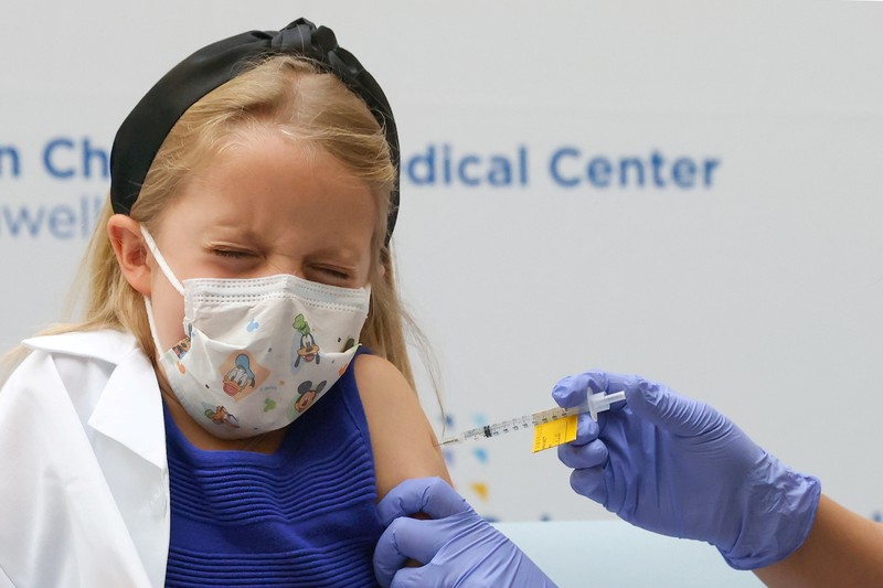 Vaksin Covid-19 Untuk Anak di AS Nora Gossett, 7, reacts as she receives the Pfizer-BioNTech COVID-19 vaccine from Sophia Jan, MD, while her father Jeff Gossett, MD, holds her hand at Cohen Children's Medical Center as vaccines were approved for children aged 5-11, amid the coronavirus disease pandemic, in New Hyde Park, New York, U.S., November 4, 2021. REUTERS/Andrew Kelly