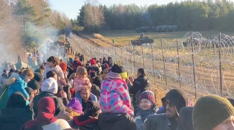Para migran berkumpul di dekat pagar kawat berduri dalam upaya melintasi perbatasan dengan Polandia di wilayah Grodno, Belarusia. (via REUTERS/OBTAINED BY REUTERS)