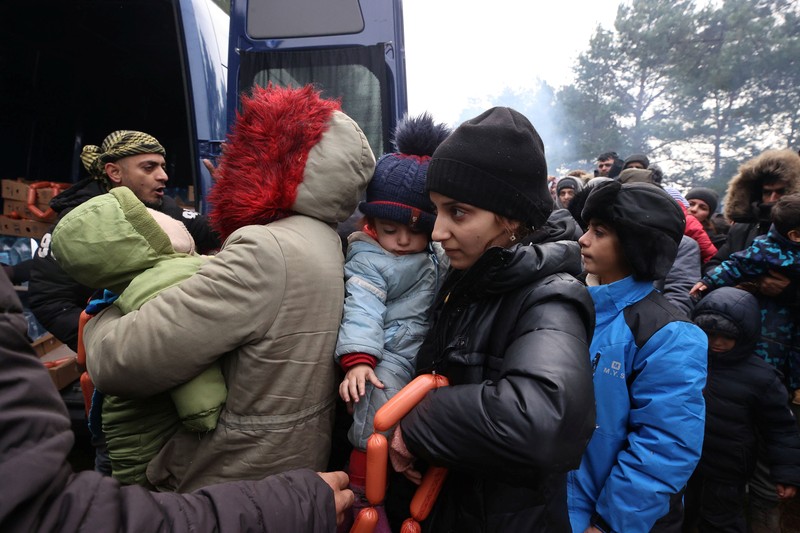 Para migran berkumpul di dekat pagar kawat berduri dalam upaya melintasi perbatasan dengan Polandia di wilayah Grodno, Belarusia. (via REUTERS/OBTAINED BY REUTERS)