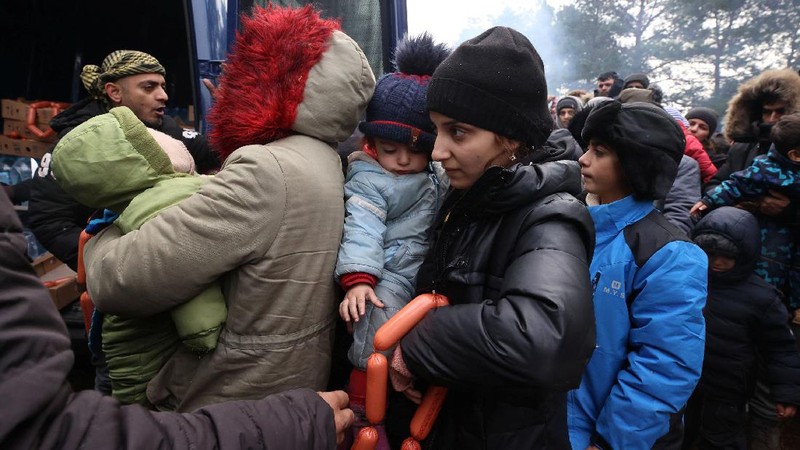 Para migran berkumpul di dekat pagar kawat berduri dalam upaya melintasi perbatasan dengan Polandia di wilayah Grodno, Belarusia. (via REUTERS/OBTAINED BY REUTERS)