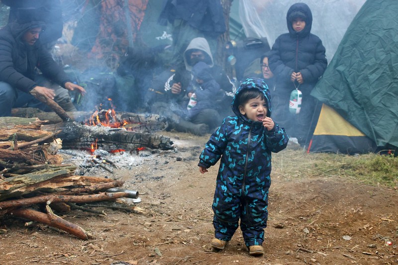 Para migran berkumpul di dekat pagar kawat berduri dalam upaya melintasi perbatasan dengan Polandia di wilayah Grodno, Belarusia. (via REUTERS/OBTAINED BY REUTERS)
