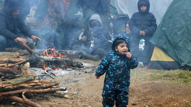 Para migran berkumpul di dekat pagar kawat berduri dalam upaya melintasi perbatasan dengan Polandia di wilayah Grodno, Belarusia. (via REUTERS/OBTAINED BY REUTERS)