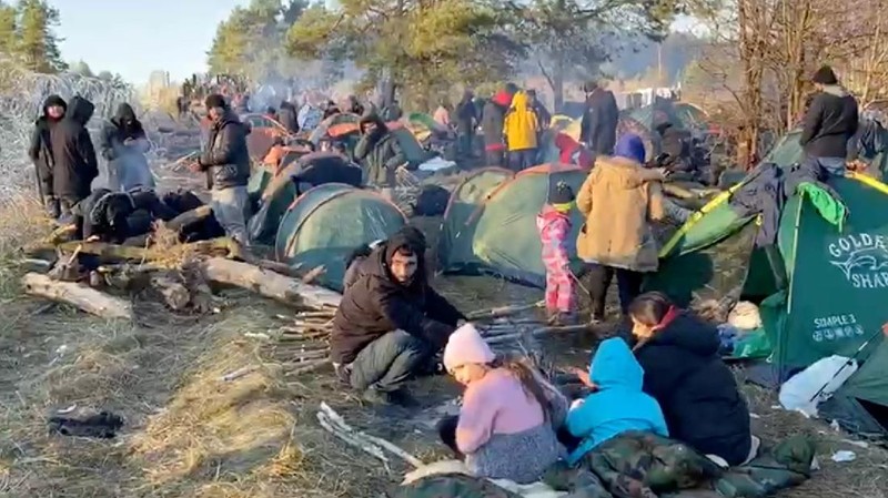 Para migran berkumpul di dekat pagar kawat berduri dalam upaya melintasi perbatasan dengan Polandia di wilayah Grodno, Belarusia. (via REUTERS/OBTAINED BY REUTERS)