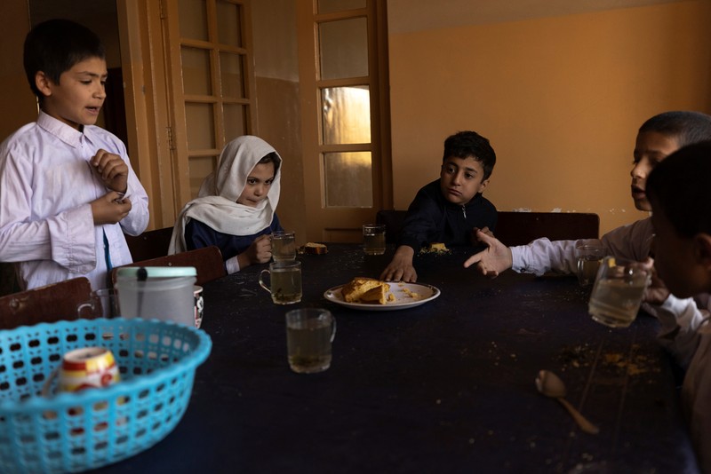 AFGHANISTAN-CONFLICT/ORPHANAGE Golshan, a childcare worker at the orphanage, serves the children tea and bread for breakfast in Kabul, Afghanistan, October 12, 2021. Orphanages like this play an outsize role in Afghanistan, where tens of thousands of civilians have been killed in wars that have ravaged the country for more than 40 years. The lack of funding, which has hit charities, non-governmental organisations and ordinary Afghans since the hardline Islamist Taliban movement took back control of the country, is forcing orphanage director Ahmad Khalil Mayan (not pictured) into tough choices.