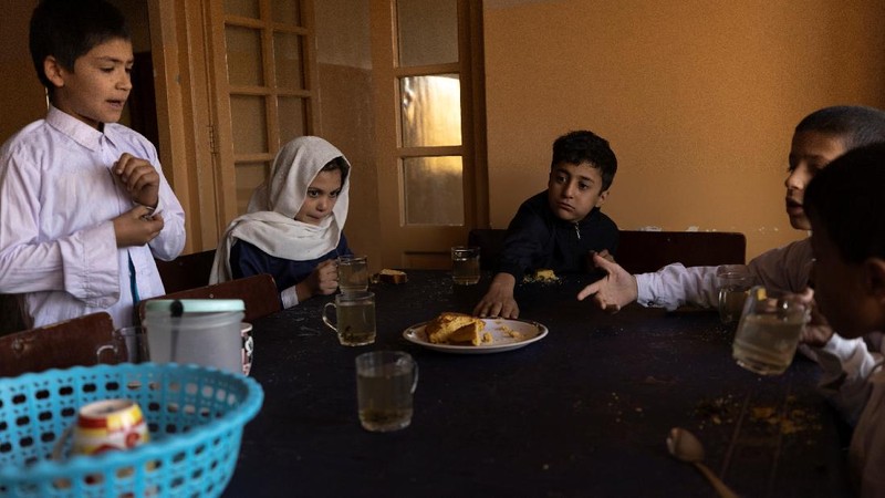 Golshan, a childcare worker at the orphanage, serves the children tea and bread for breakfast in Kabul, Afghanistan, October 12, 2021. Orphanages like this play an outsize role in Afghanistan, where tens of thousands of civilians have been killed in wars that have ravaged the country for more than 40 years. The lack of funding, which has hit charities, non-governmental organisations and ordinary Afghans since the hardline Islamist Taliban movement took back control of the country, is forcing orphanage director Ahmad Khalil Mayan (not pictured) into tough choices. 