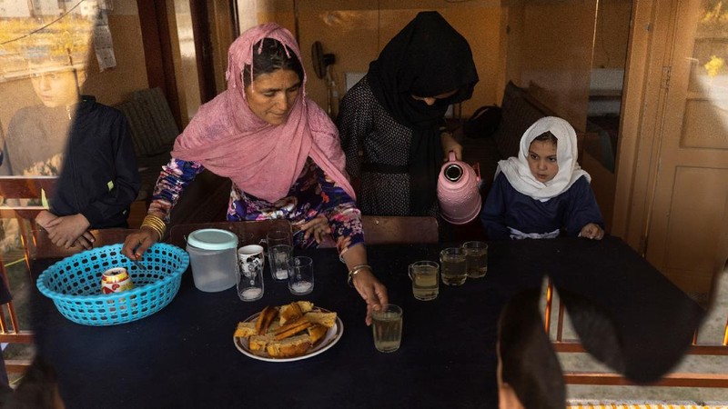 Golshan, a childcare worker at the orphanage, serves the children tea and bread for breakfast in Kabul, Afghanistan, October 12, 2021. Orphanages like this play an outsize role in Afghanistan, where tens of thousands of civilians have been killed in wars that have ravaged the country for more than 40 years. The lack of funding, which has hit charities, non-governmental organisations and ordinary Afghans since the hardline Islamist Taliban movement took back control of the country, is forcing orphanage director Ahmad Khalil Mayan (not pictured) into tough choices. 
