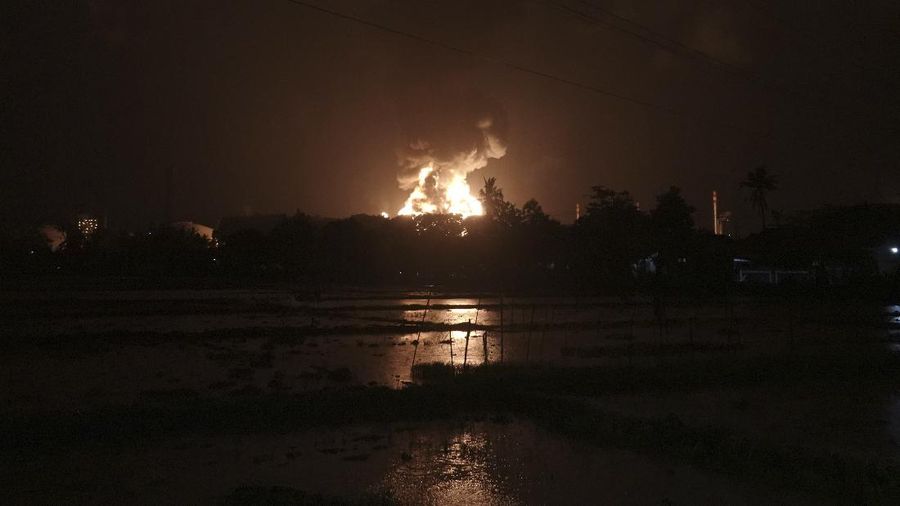 The sky glows from the fire that razes through an oil refinery owned by the national oil company Pertamina, in Cilacap, Central Java, Indonesia, Saturday, Nov. 13, 2021. The fire at a gasoline storage at the largest oil refinery on Indonesia's Java island prompted the evacuation of dozens of residents living nearby. (AP Photo/Agus Fitrah)